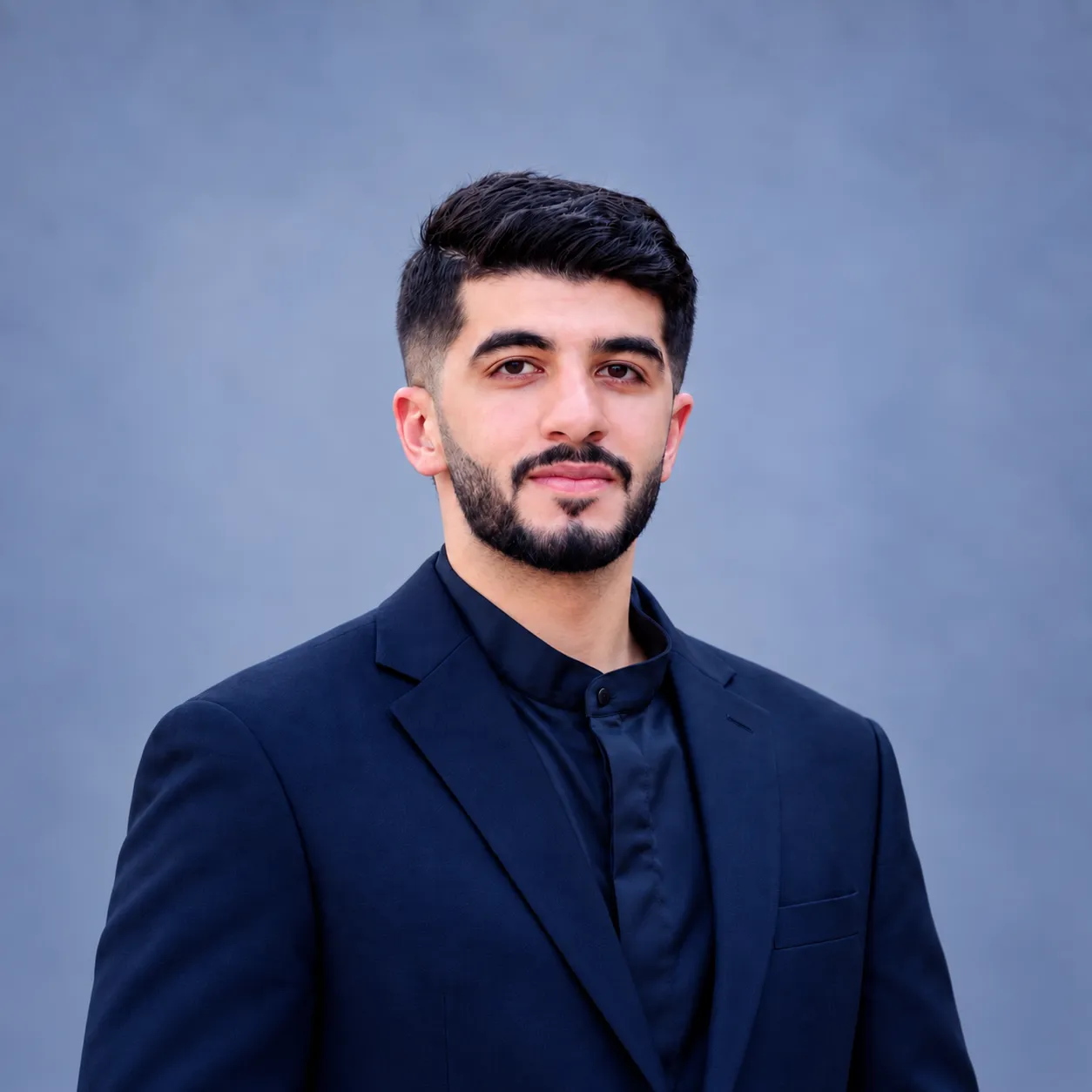 Abed Fataftah, wearing a navy suit jacket over a dark shirt.